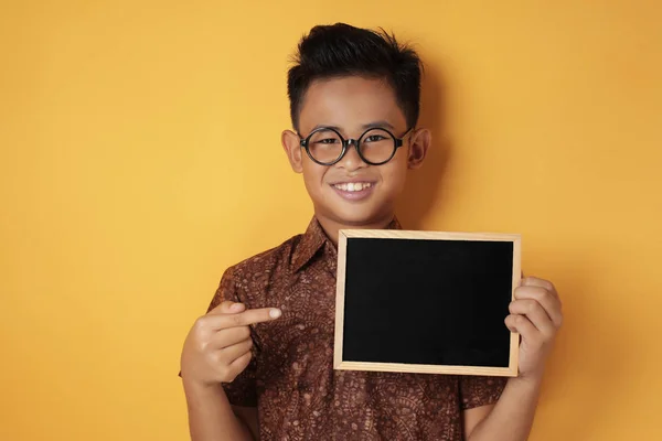 Inteligente asiático chico sonriendo en cámara y mostrando vacío pizarra — Foto de Stock