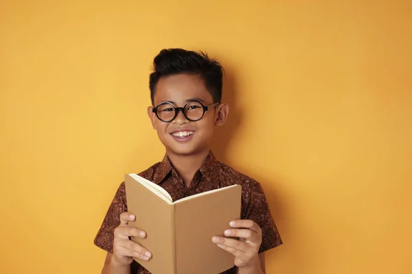 Inteligente asiático chico sonriendo mientras leyendo libro — Foto de Stock