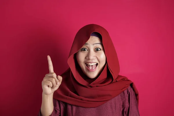 Mulher muçulmana tendo uma ideia brilhante, olhando para a câmera sorrindo e apontando para cima — Fotografia de Stock