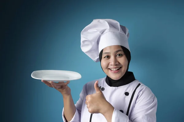 Aziatische vrouwelijke chef-kok toont lege witte plaat, presenteren iets, — Stockfoto