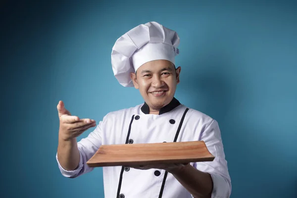 Aziatisch man chef-kok toont lege houten plaat, presenteren iets, — Stockfoto