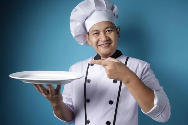 Asian Male Chef Shows Empty White Plate, Presenting Something, C — Stock Photo, Image