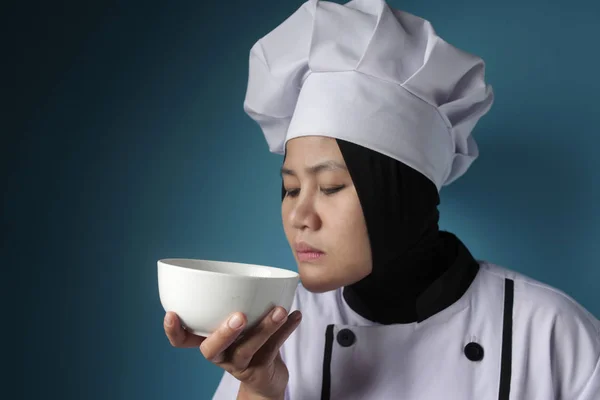 Aziatische vrouw chef-kok ruiken voedsel in witte schaal — Stockfoto
