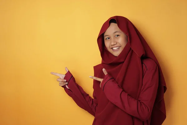 Menina adolescente muçulmana sorrindo e apontando para o lado com cópia — Fotografia de Stock