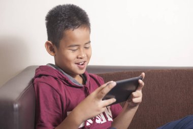 Genç Asyalı çocuk tablet akıllı telefonda online oyunlar oynuyor