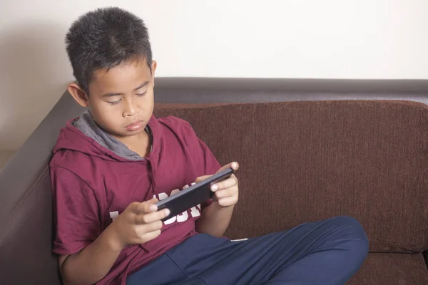 Mladý asijský chlapec hrát online hry na tablet chytrý telefon — Stock fotografie