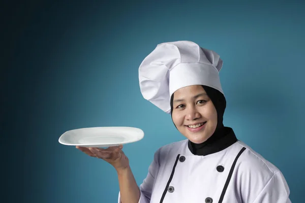 Aziatische vrouwelijke chef-kok toont lege witte plaat, presenteren iets, — Stockfoto