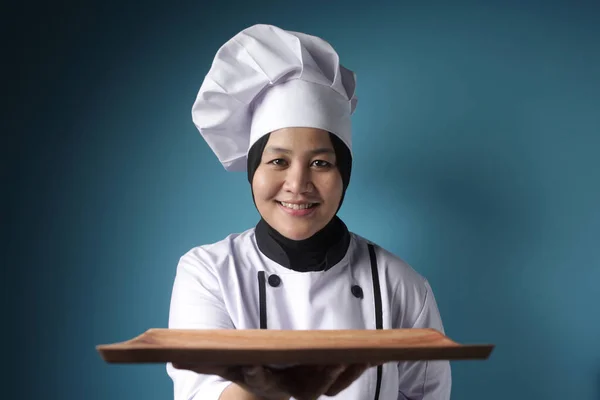 Aziatische vrouwelijke chef-kok toont lege houten plaat, presenteren iets — Stockfoto