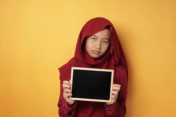 Droevig aziatisch moslim tiener meisje tonen lege schoolbord — Stockfoto