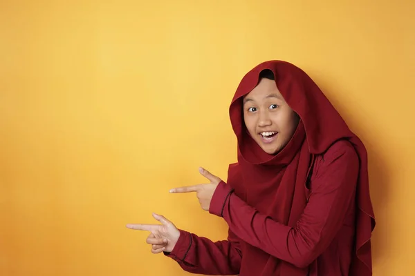 Menina adolescente muçulmana sorrindo e apontando para o lado com cópia — Fotografia de Stock