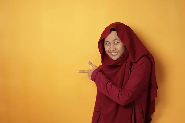 Menina adolescente muçulmana sorrindo e apontando para o lado com cópia — Fotografia de Stock