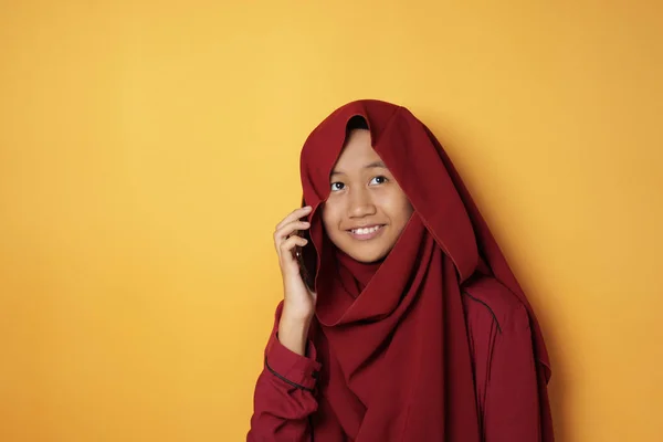 Азиатская мусульманская девочка-подросток улыбается, разговаривая по телефону — стоковое фото