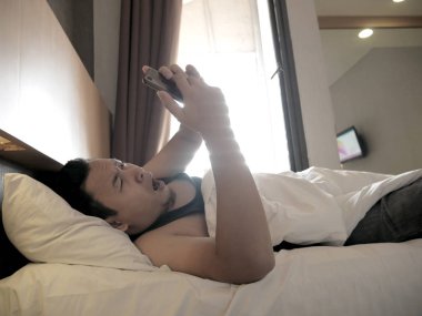 Telefon bağımlısı konsepti, Asyalı adam akıllı telefonunu kontrol ediyor.