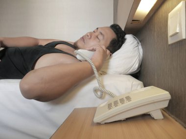 Sabahleyin yatakta uyandığında Asyalı adam telefona cevap veriyor.