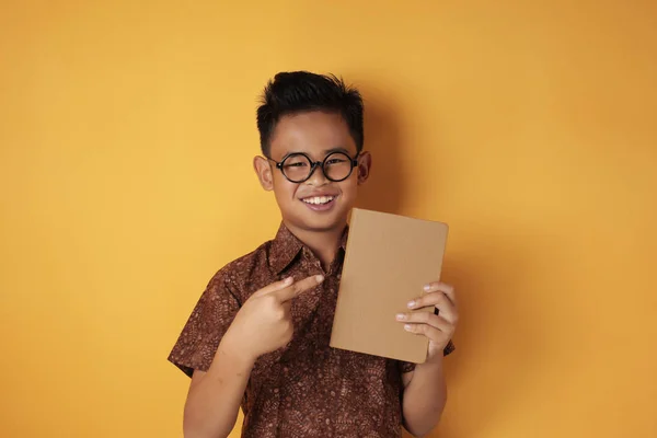 Aziatische student jongen holding boek en glimlachen op camera — Stockfoto