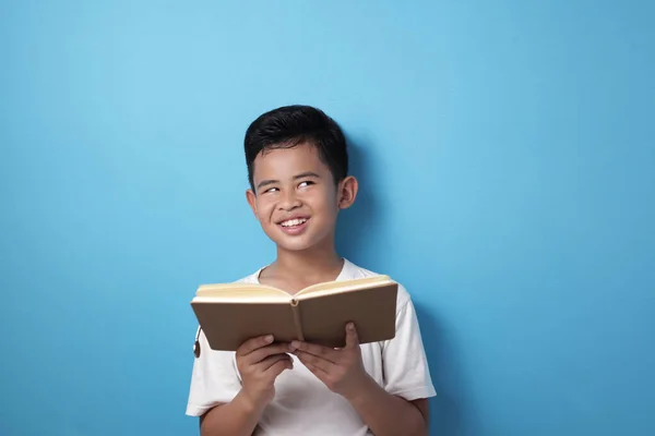 Asiatisk pojke tittar upp tänkande uttryck när du läser en bok — Stockfoto