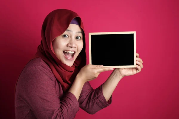 Розумна азіатська мусульманка, що посміхається в камері і показує порожній Бл — стокове фото
