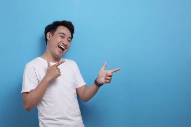 Yan tarafı gösteren mutlu Asyalı genç adam, fotokopi alanı olan bir şey sunuyor.