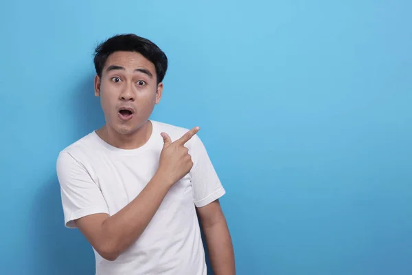 Glad asiatisk ung man pekar åt sidan, presentera något med kopieringsutrymme — Stockfoto