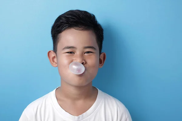 Lindo asiático chico comer burbuja chicle y golpe globo — Foto de Stock
