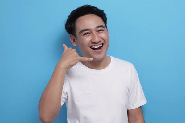 Young Asian male smiling and shows call me telephone hand sign gesture — 스톡 사진