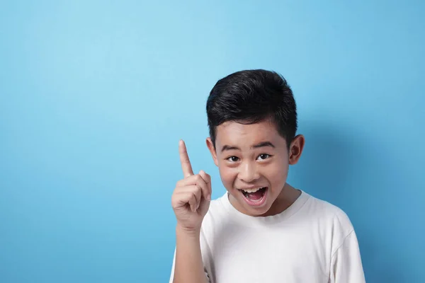 Glücklicher asiatischer Junge zeigt mit erhobenem Zeigefinger auf Idee Geste — Stockfoto