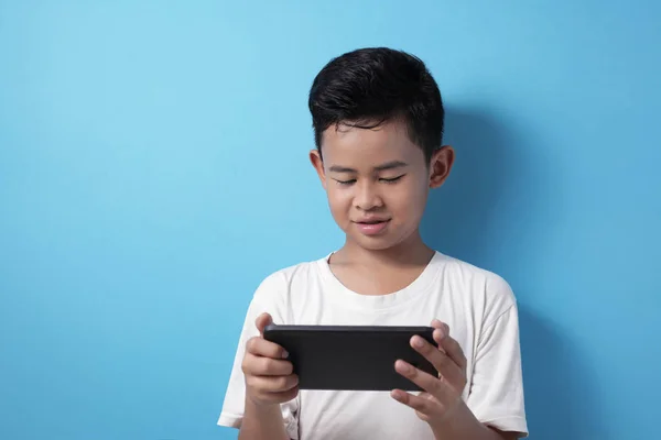 Asiático chico juega en línea juego en su tableta gadget — Foto de Stock