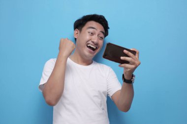 Komik genç Asyalı adam tablete oyunlar oynarken