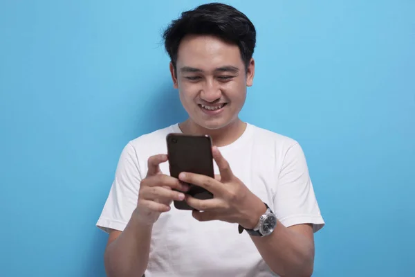 Joven Mensajes de texto de lectura de chat en su teléfono, sonriendo feliz — Foto de Stock