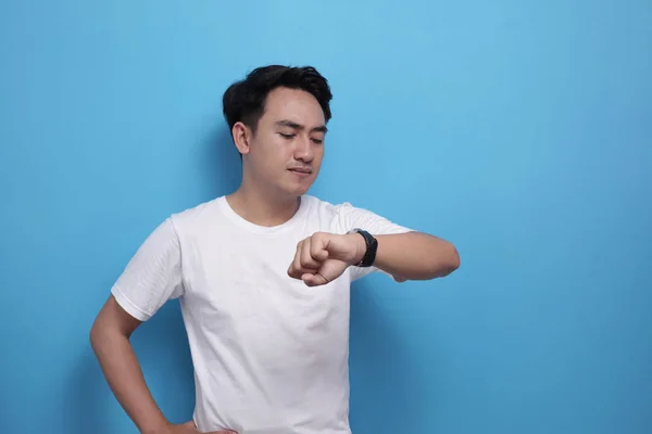 Ung asiatisk manlig student kollar tiden på handledsklockan — Stockfoto
