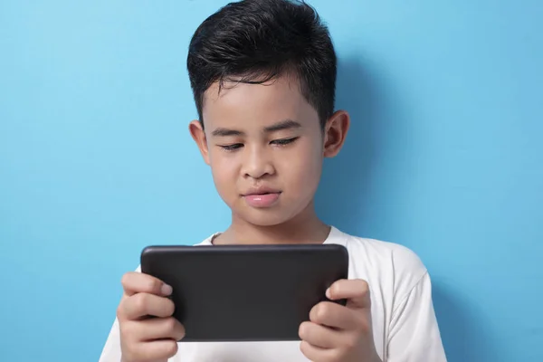 Asiático chico juega en línea juego en su tableta gadget — Foto de Stock
