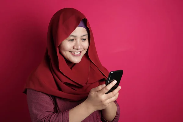 スマートフォンでメッセージを読みながら微笑むムスリム女性 — ストック写真