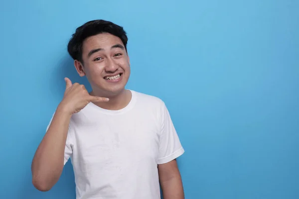 Young Asian male smiling and shows call me telephone hand sign gesture — 스톡 사진