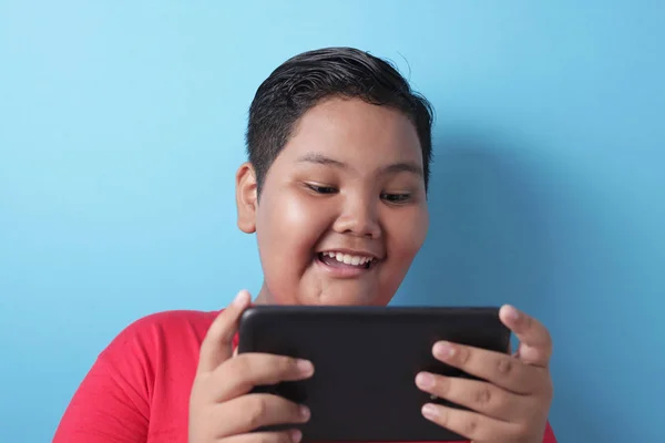 Tlustý asijský chlapec hraje online hry na jeho tablet gadget — Stock fotografie