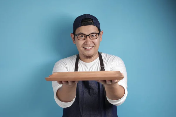Asian Male Chef or Waiter Shows Empty Wooden Plate, Presenting S — Stock Photo, Image