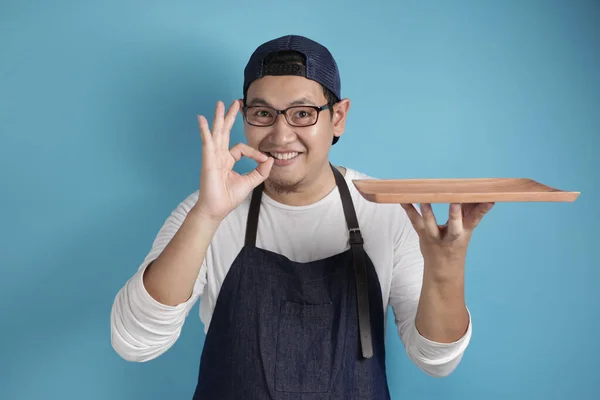 Asian Male Chef or Waiter Shows Empty Wooden Plate, Presenting S