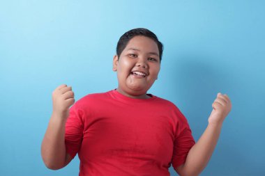 Happy success fat Asian boy shows winning gesture