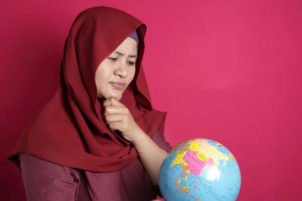 Mulher muçulmana feliz vestindo hijab vermelho pensando enquanto segurando eart — Fotografia de Stock