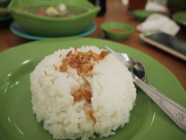 Bir kase sığır eti çorbası ile servis edilen yeşil tabakta beyaz pirinç.