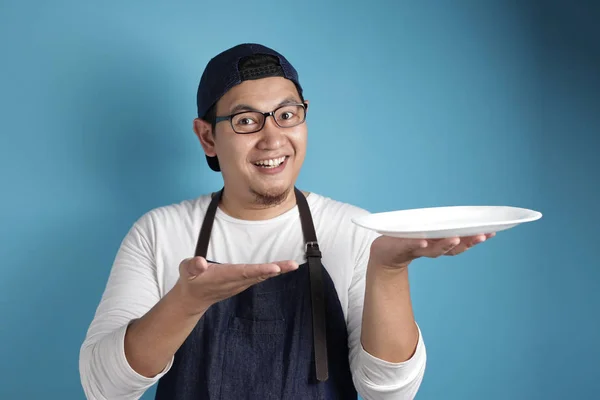 Asian Male Chef or Waiter Shows Empty White Plate, Presenting So — Stock Photo, Image