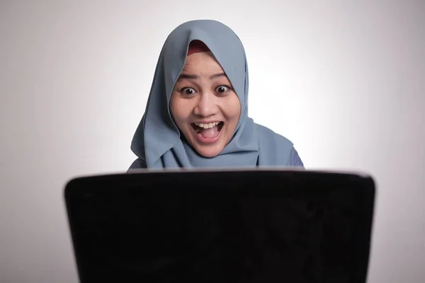 Мусульманська жінка, що працює на ноутбуці, шокована приголомшеними почуттями — стокове фото