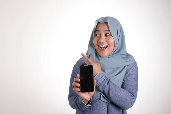 Muslimische Frau hält Telefon in der Hand und zeigt auf die Seite — Stockfoto