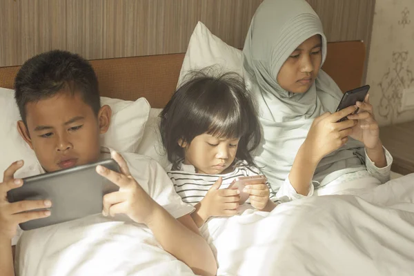 Little kids sister and brother siblings plays on gadget smart phone, phone addiction on children concept