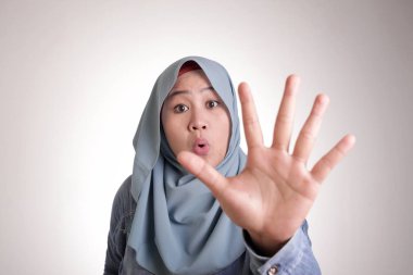 Portrait of muslim lady wearing hijab shows stop sign, prohibit forbid disallow something bad with palm hand gesture