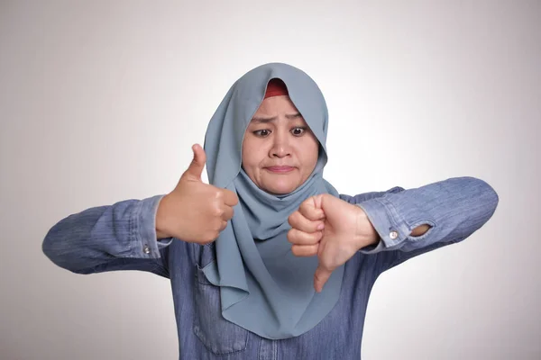 亚洲穆斯林妇女的形象表现出大拇指上下摆动的姿态 好的和坏的决策观念 — 图库照片