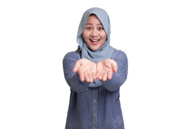 Tesettürlü Asyalı müslüman kadının portresi gülümsüyor ve boş ellerinde fotokopi alanı şablonu sunan bir şey gösteriyor.