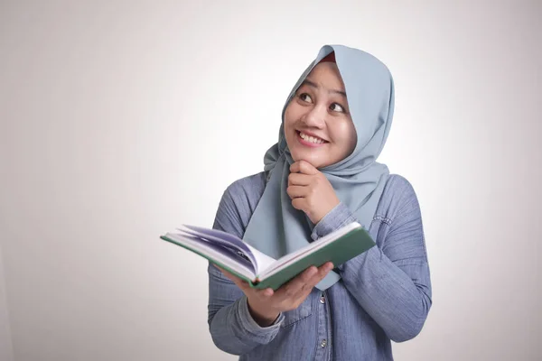 年轻的亚洲穆斯林女子的画像 在阅读一本书时 手指尖着 微笑着 有很好的意念 被白色隔离 — 图库照片