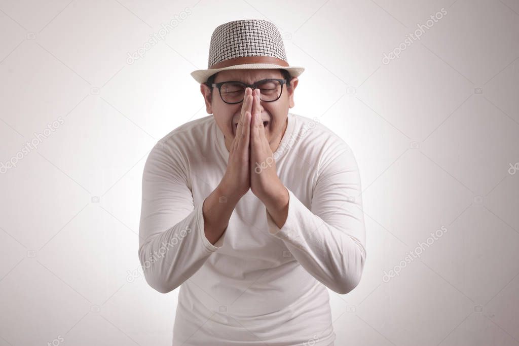 Young Asian man wearing casual grey shirt regret, apologize gesture. Close up body portrait