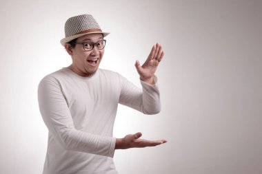 Mutlu Genç Asyalı adam ellerini kopya alanı şablonu beyaz arka plan üzerinde arasında bir şey gösterilen portresi