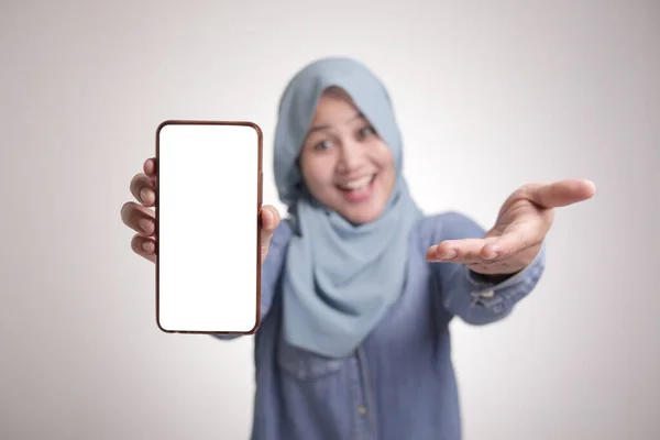 アジアのイスラム教徒の女性の肖像画は カメラの笑顔を見て 彼女のスマートフォンを示しています 電話モックアップ 白に隔離されました — ストック写真
